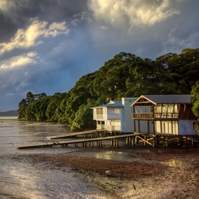 white cottage sitting by a bay under a cloudy sunset